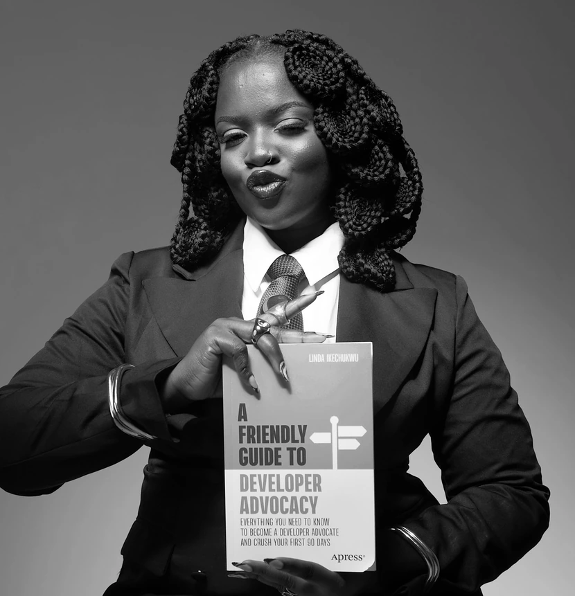 Linda Ikechukwu holding her book, A Friendly Guide to Developer Advocacy